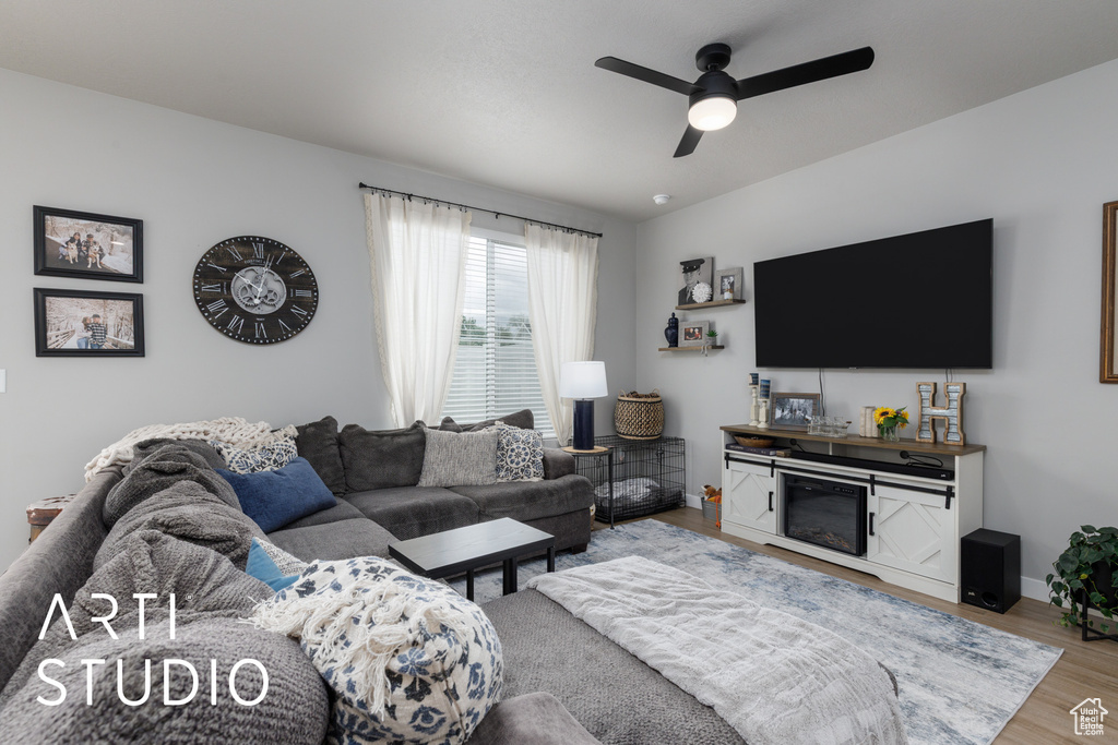 Living area with a ceiling fan, wood finished floors, and baseboards