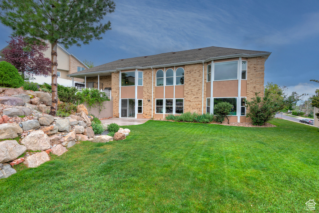 Back of property featuring a lawn, brick siding, and a patio