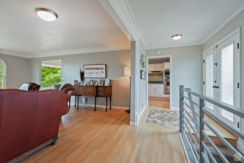 Living room with light wood-type flooring, crown molding, and baseboards