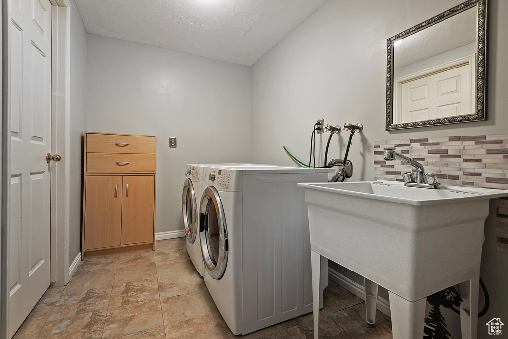 Washroom featuring light stone finish floors, baseboards, and washer and clothes dryer