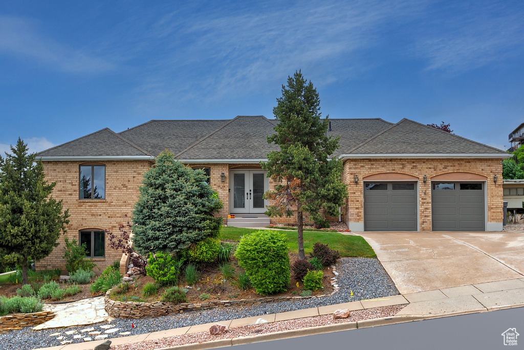 View of front of house featuring brick siding, french doors, a garage, a shingled roof, and concrete driveway