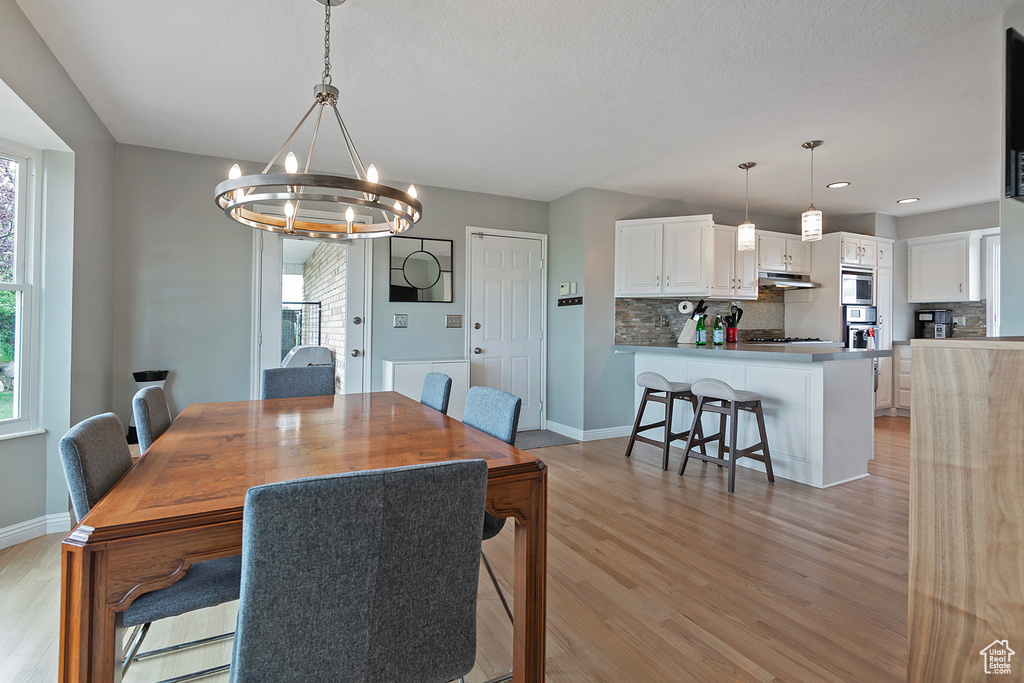 Dining space featuring a chandelier, light wood-type flooring, baseboards, and recessed lighting