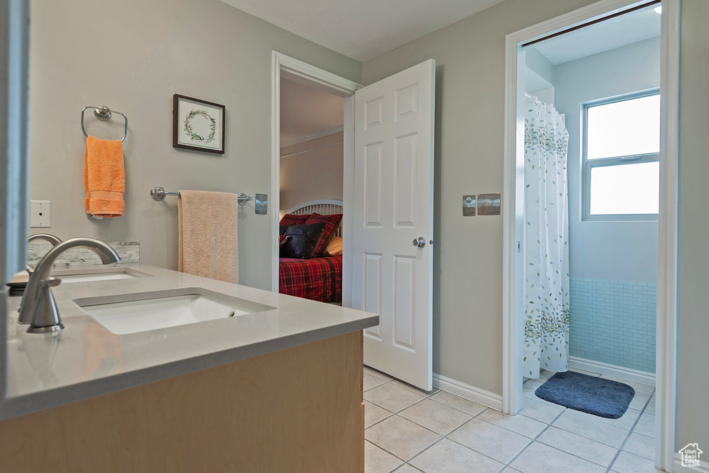 Bathroom featuring tile patterned flooring, double vanity, curtained shower, and baseboards