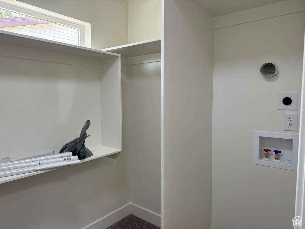 Washroom with hookup for an electric dryer, hookup for a washing machine, and baseboards