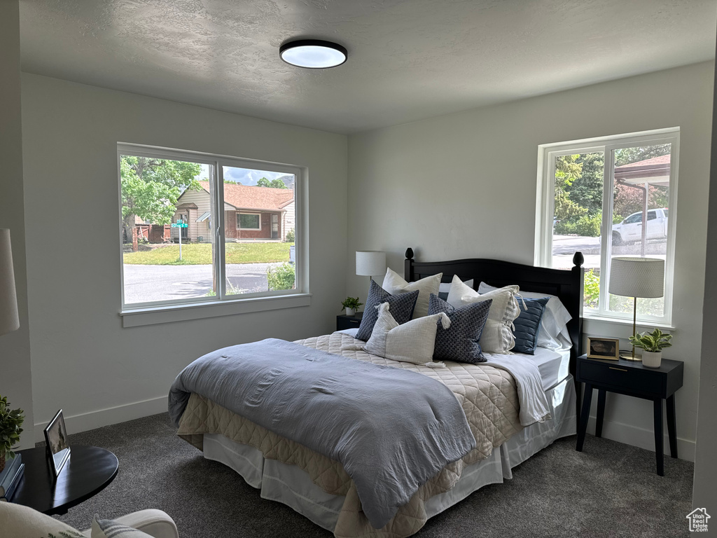 Bedroom featuring dark carpet and baseboards