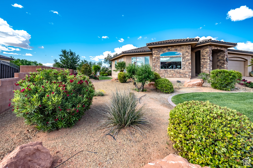 View of home\\\'s exterior with stone siding, a tile roof, fence, stucco siding, and a garage