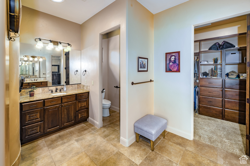 Bathroom with toilet, vanity, tile patterned flooring, and baseboards