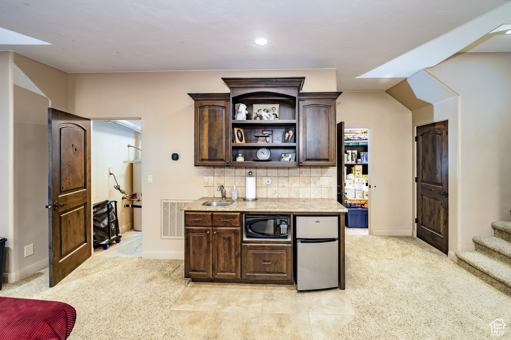 Bar with black microwave, fridge, a sink, tasteful backsplash, and baseboards