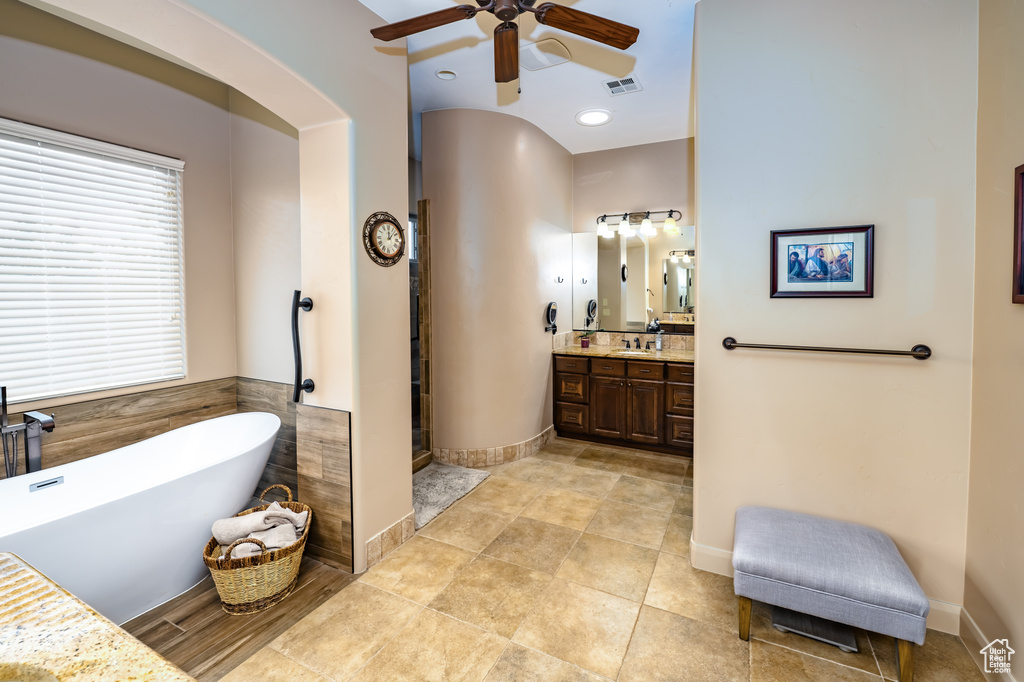Bathroom featuring ceiling fan, a freestanding bath, vanity, a stall shower, and tile patterned flooring
