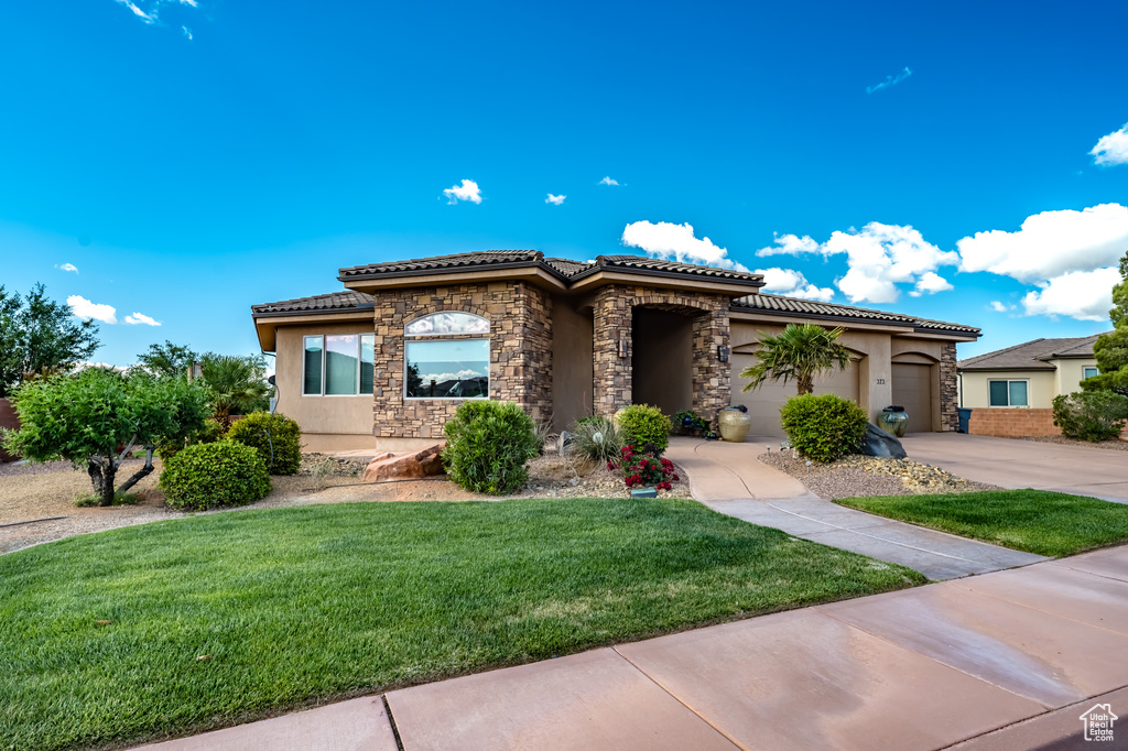 Mediterranean / spanish-style home with driveway, stucco siding, a tile roof, and stone siding