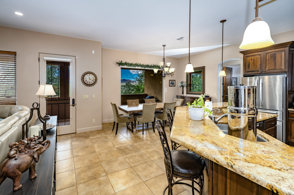 Kitchen with light stone counters, freestanding refrigerator, healthy amount of natural light, a chandelier, and recessed lighting