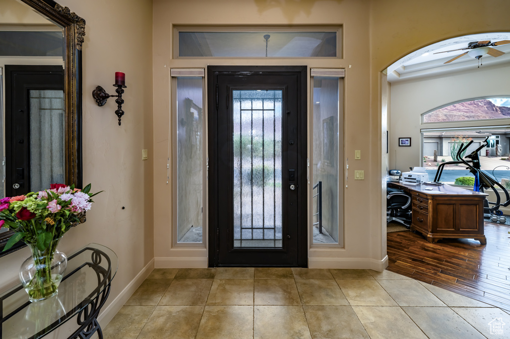 Entrance foyer featuring baseboards, a ceiling fan, arched walkways, and light tile patterned floors