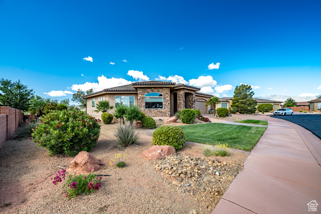 Mediterranean / spanish home featuring stone siding, a tiled roof, fence, a garage, and driveway