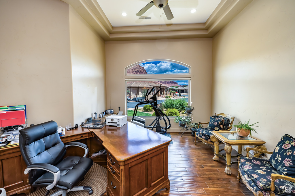 Office space featuring dark wood-style flooring, a ceiling fan, a tray ceiling, and a high ceiling