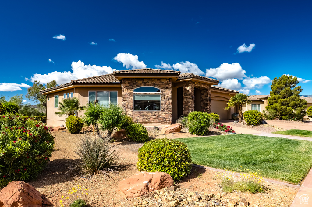 Mediterranean / spanish house featuring stone siding, a tiled roof, an attached garage, and stucco siding