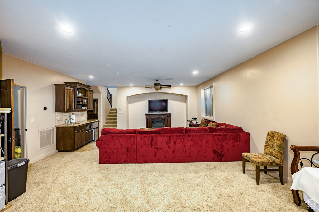 Living area with light colored carpet, stairway, a fireplace, a ceiling fan, and recessed lighting