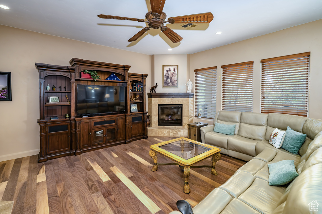 Living area featuring a ceiling fan, wood finished floors, recessed lighting, baseboards, and a fireplace