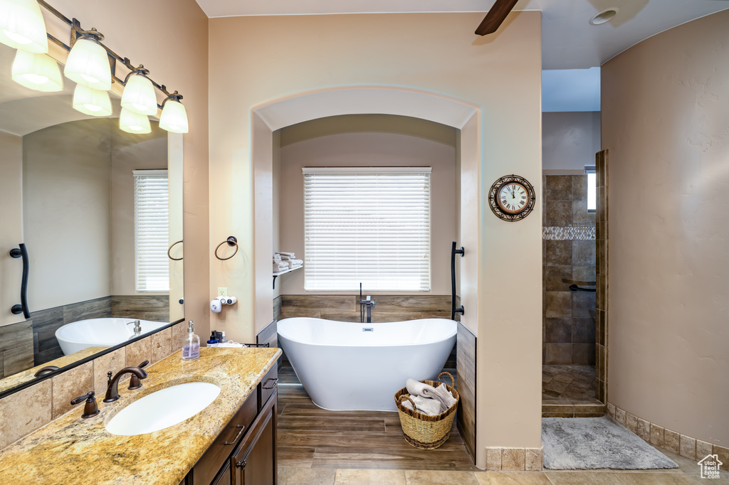 Bathroom featuring a soaking tub, vanity, and a tile shower