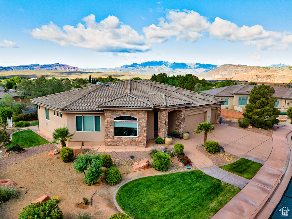 Mediterranean / spanish-style home featuring stone siding, a mountain view, driveway, and stucco siding
