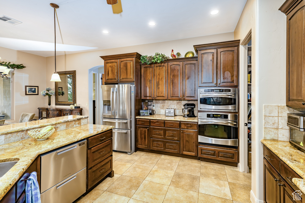 Kitchen with stainless steel appliances, decorative backsplash, decorative light fixtures, a ceiling fan, and recessed lighting