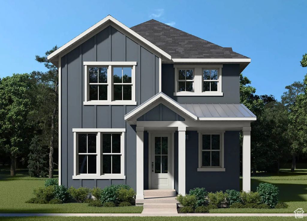 View of front of home with board and batten siding, a front lawn, and roof with shingles