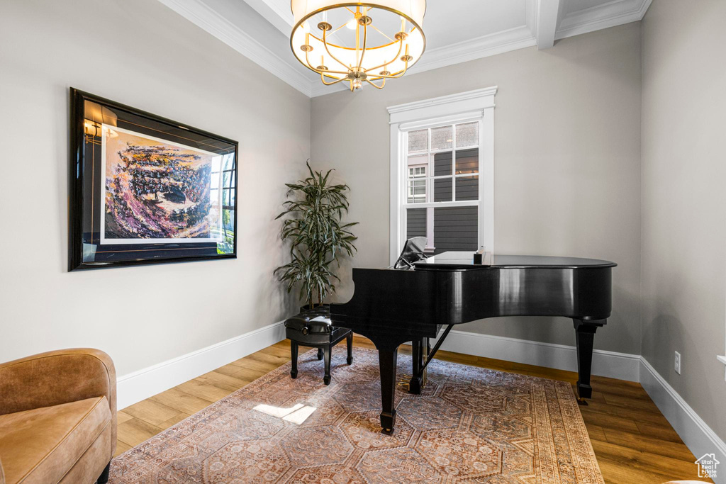 Living area featuring crown molding, a chandelier, wood finished floors, and baseboards