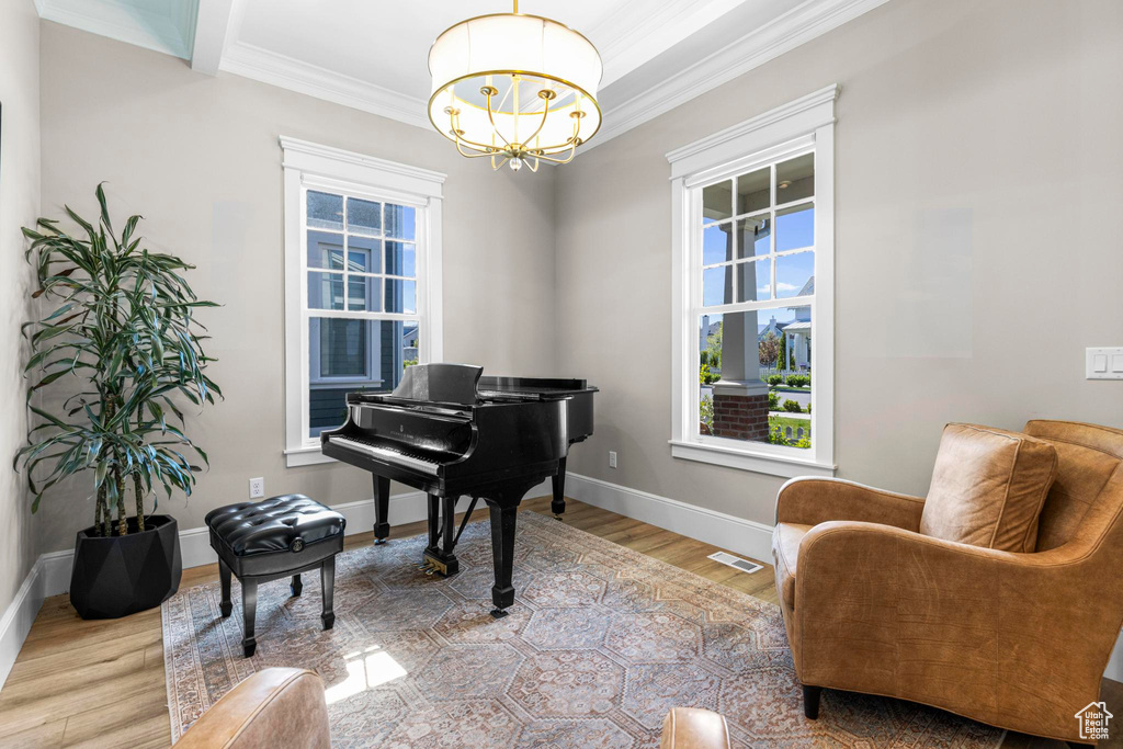 Sitting room featuring a chandelier, ornamental molding, plenty of natural light, wood finished floors, and baseboards