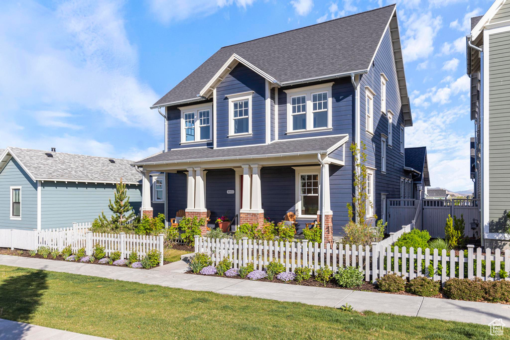 Craftsman house with a porch, a fenced front yard, and a shingled roof