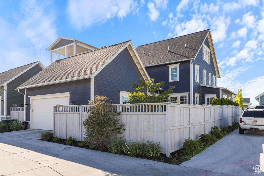 View of home\'s exterior with roof with shingles, concrete driveway, fence, and a garage