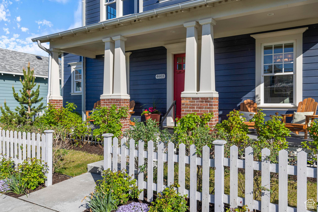 Property entrance with a porch, fence, and brick siding