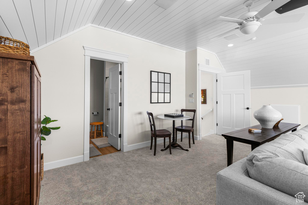 Living room with vaulted ceiling, wood ceiling, carpet floors, a ceiling fan, and baseboards
