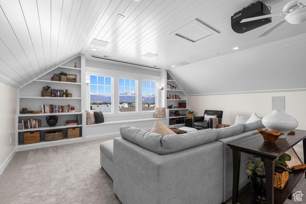 Living room with lofted ceiling, built in shelves, carpet flooring, wooden ceiling, and baseboards