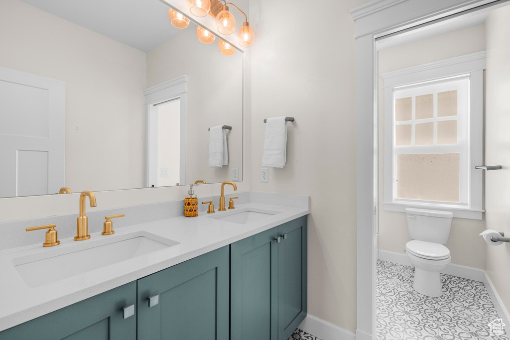 Full bath with baseboards, toilet, double vanity, and tile patterned flooring