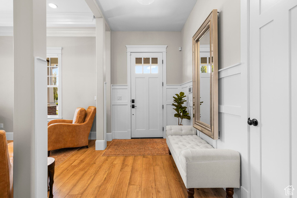 Entryway featuring light wood-type flooring, wainscoting, recessed lighting, and a decorative wall
