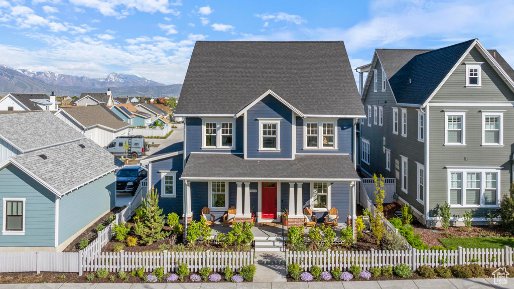 View of front facade with a porch, a mountain view, a shingled roof, a residential view, and a fenced front yard