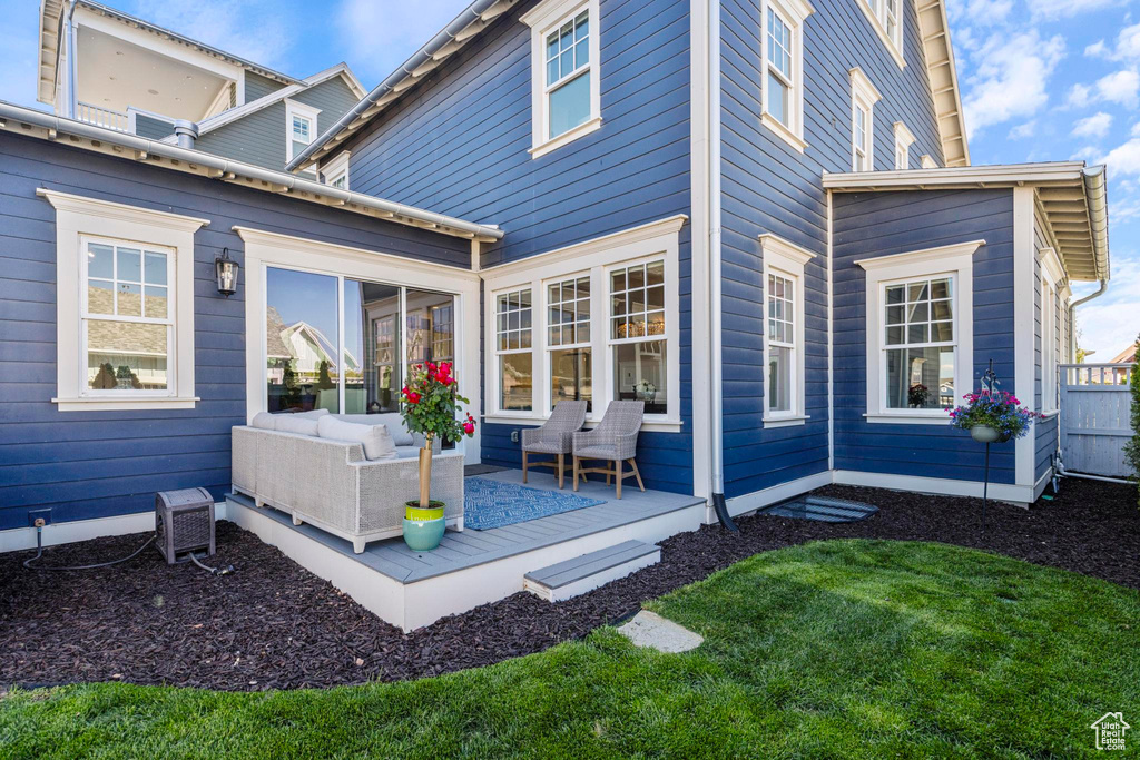Rear view of house with an outdoor hangout area, a deck, and a lawn