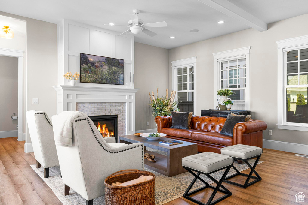 Living room with light wood-style flooring, a glass covered fireplace, baseboards, a ceiling fan, and recessed lighting