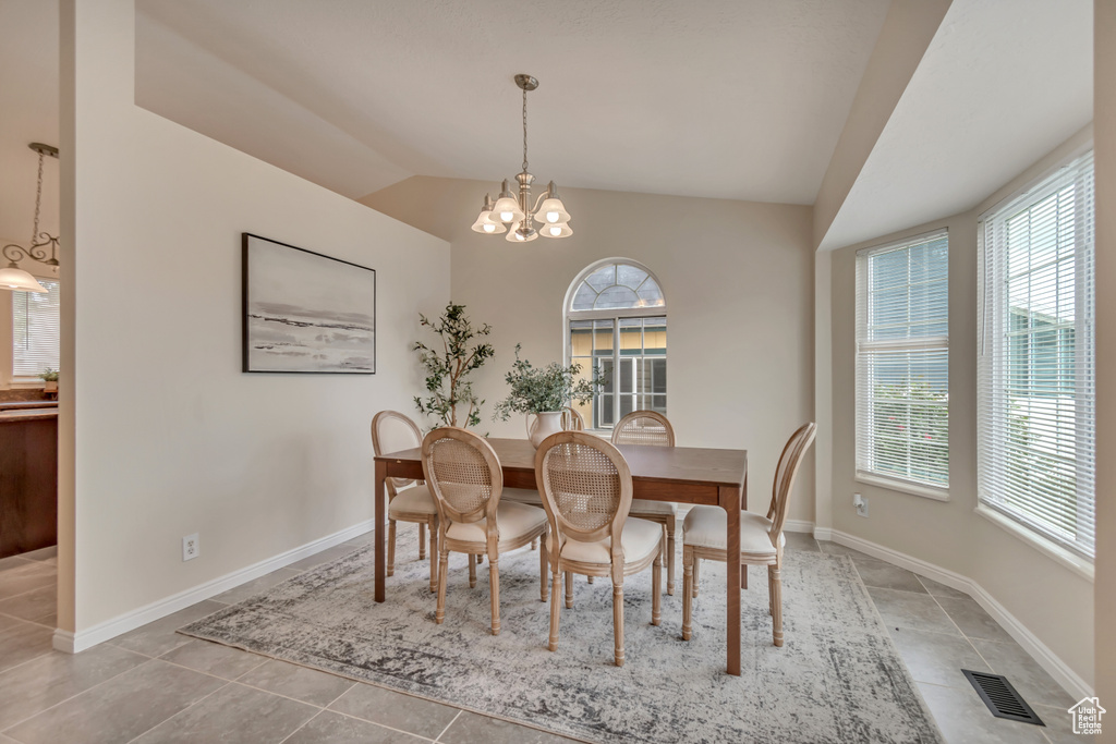 Dining room featuring lofted ceiling, a chandelier, light tile patterned floors, and baseboards