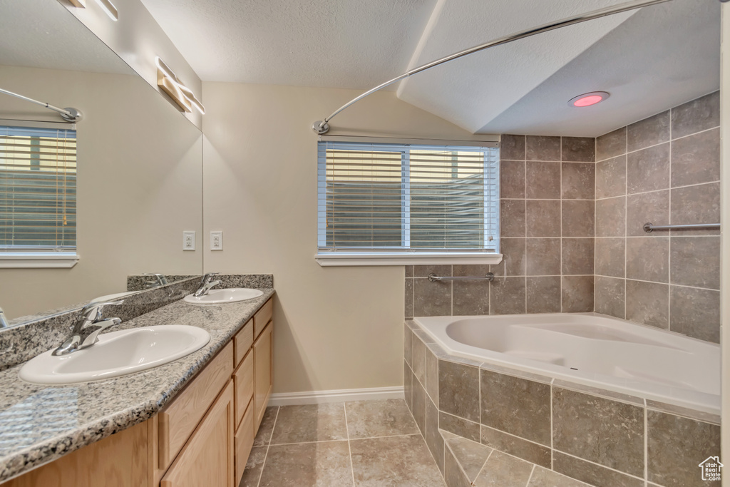 Full bath featuring baseboards, tile patterned floors, double vanity, and a textured ceiling
