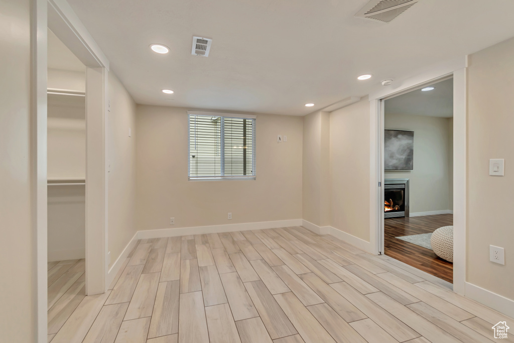 Unfurnished bedroom with recessed lighting, light wood-type flooring, a lit fireplace, baseboards, and a spacious closet