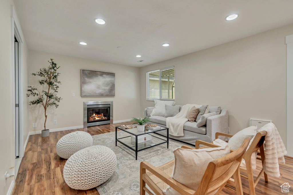 Living room with light wood-type flooring, baseboards, recessed lighting, and a glass covered fireplace