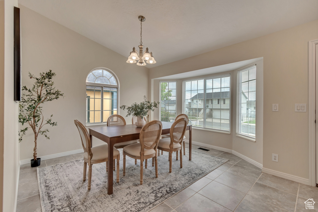 Dining space featuring a chandelier, light tile patterned floors, baseboards, and lofted ceiling