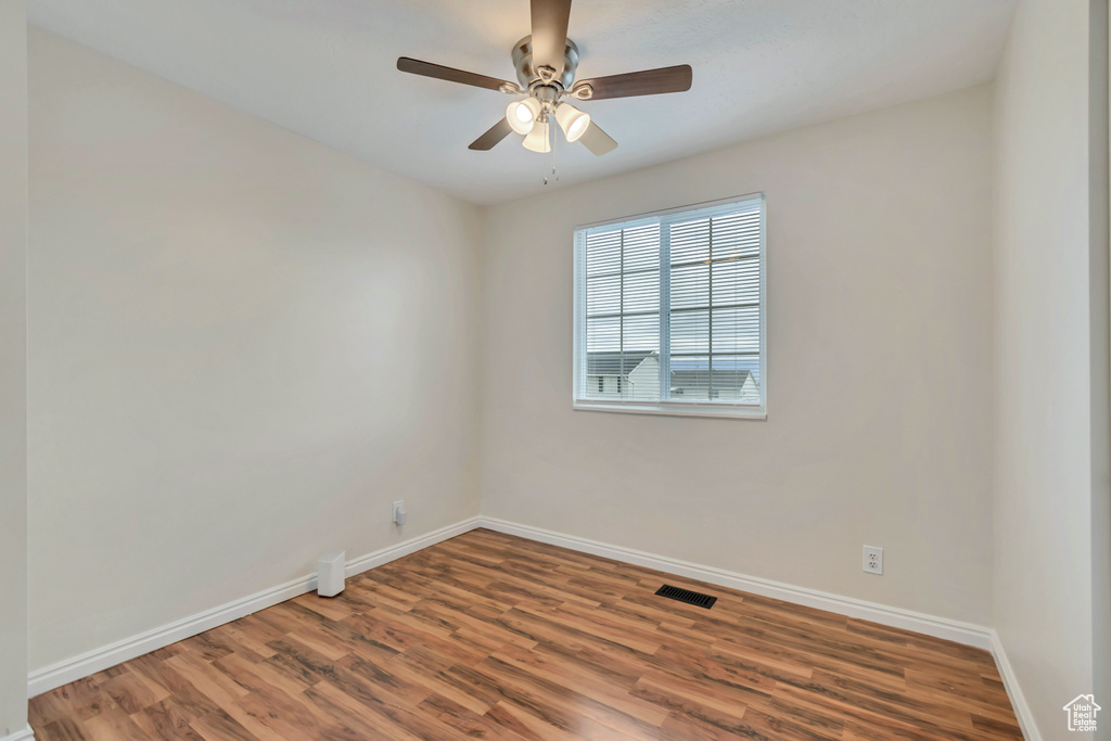 Unfurnished room featuring baseboards, wood finished floors, and a ceiling fan