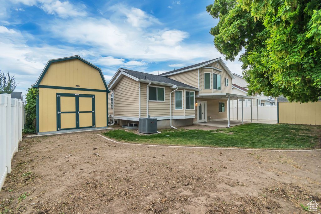 Back of property with a storage shed, a patio, an outdoor structure, and central AC