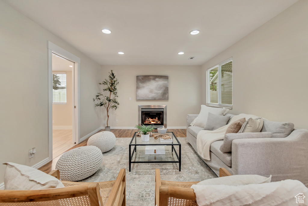 Living room featuring recessed lighting, light wood-style flooring, plenty of natural light, baseboards, and a lit fireplace