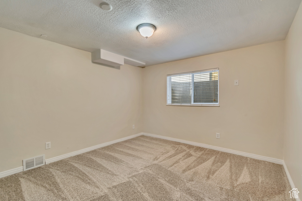 Carpeted spare room with a textured ceiling and baseboards