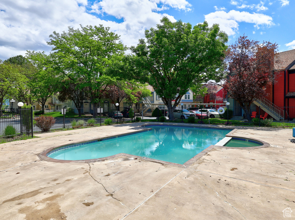 View of swimming pool featuring a patio, fence, a pool with connected hot tub, a residential view, and stairs