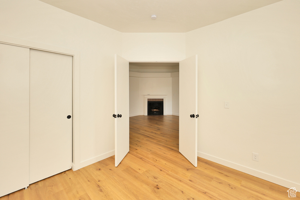 Unfurnished bedroom with light wood finished floors, a fireplace, baseboards, and a closet