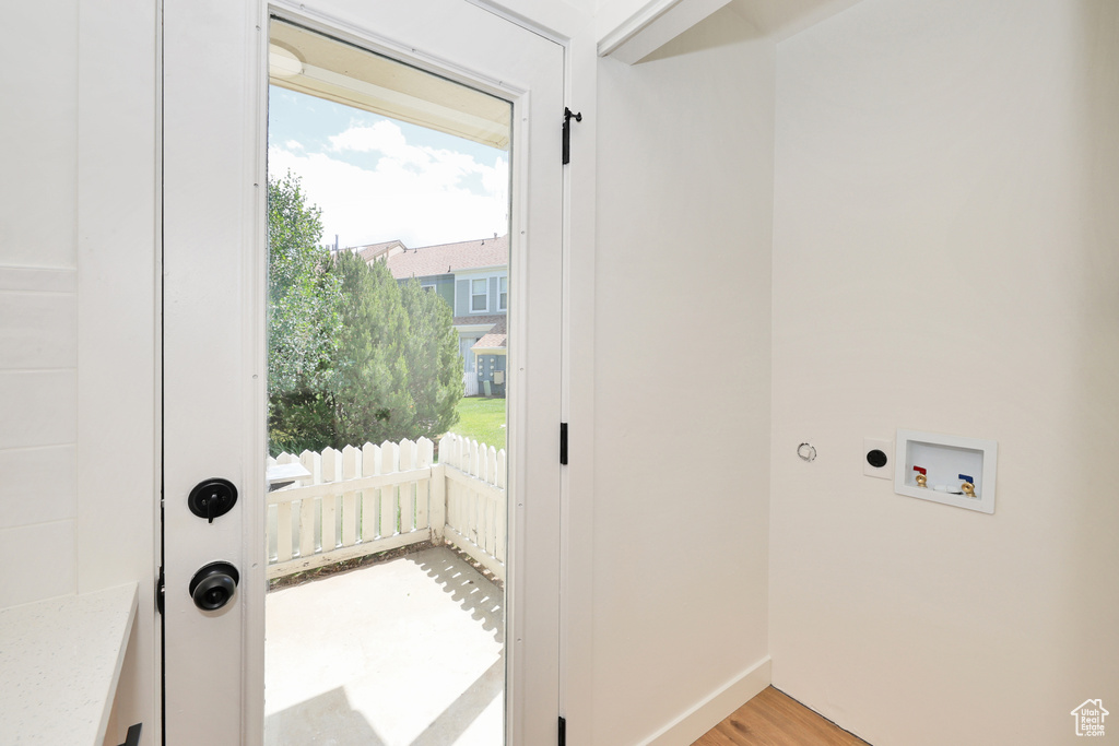 Doorway to outside featuring light wood-type flooring and baseboards