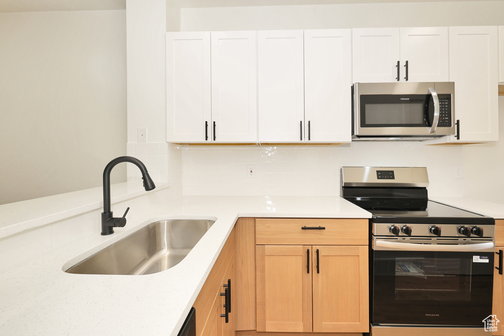 Kitchen featuring appliances with stainless steel finishes, a sink, and white cabinets